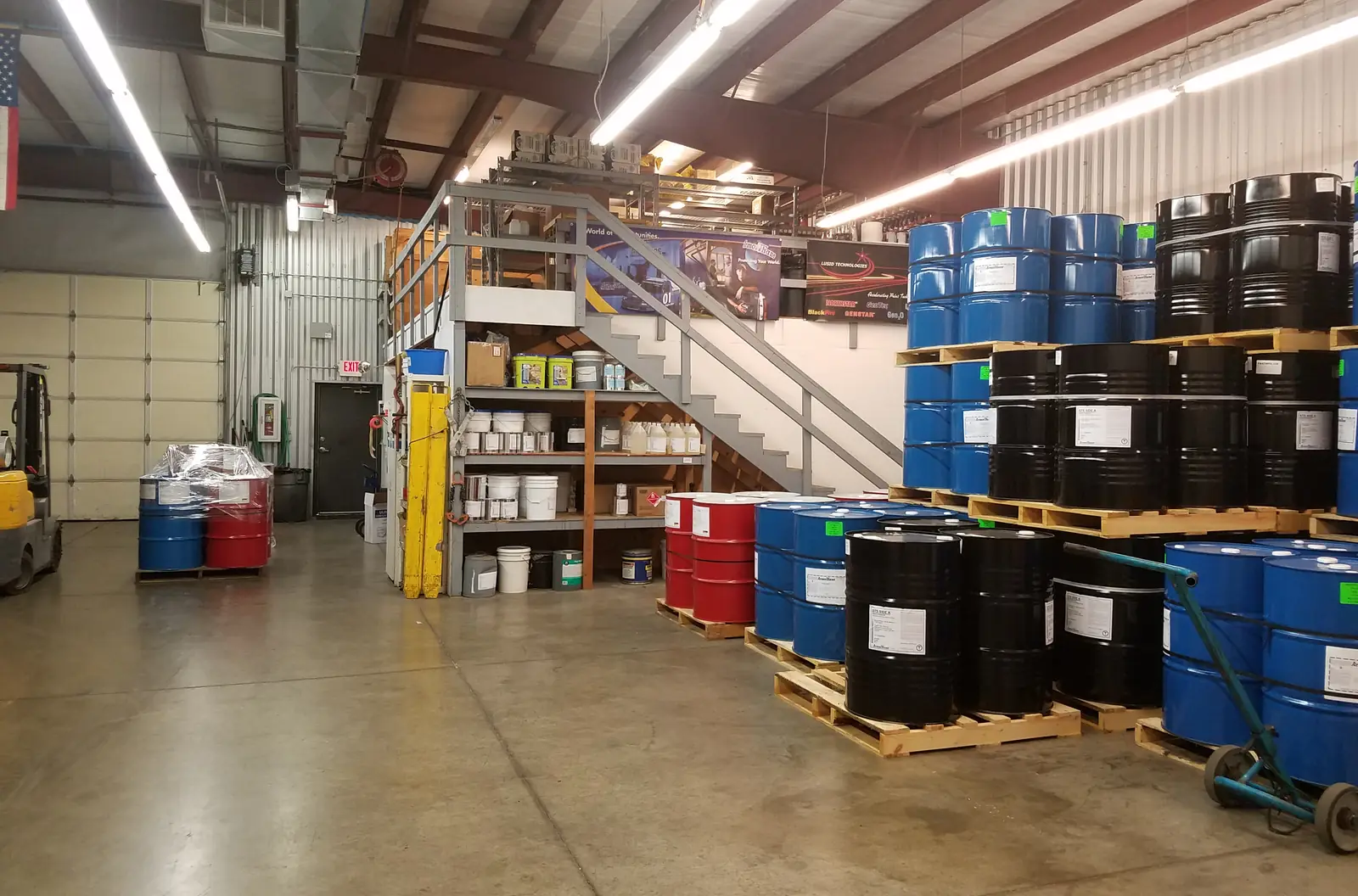 Blue drums and totes stored on pallets on a sealed warehouse floor
